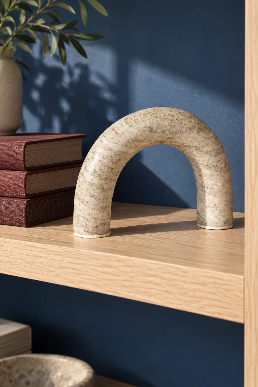 A rounded beige marble arch styled with books on a shelf.